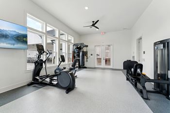 A spacious gym with a variety of equipment including treadmills, stationary bikes, and weight machines.
